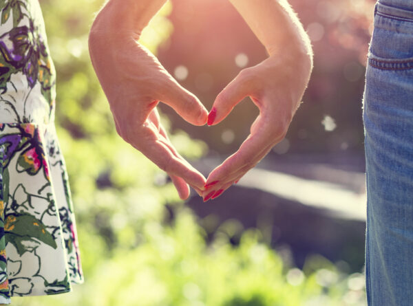 Young couple in love holding hands in the sunset in summer evening. Bright toning picture