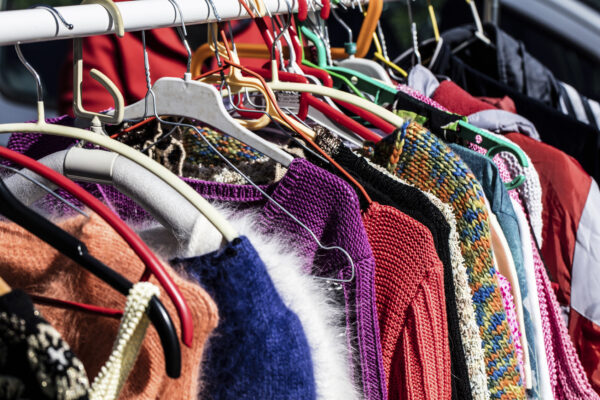 rack of fast fashion colorful women's sweaters on display for reselling,recycling,donation,reusing or welfare for second life sold at flea market, outdoors