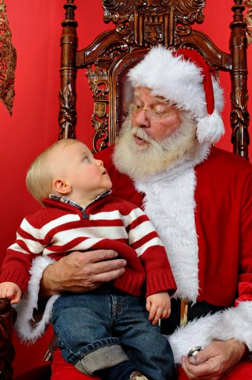 Baby boy sitting on Santa's lap at Christmas time.